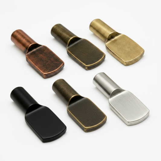 Five metal hardware pieces with a flat rectangular head are arranged in a row on a white background. From left to right, the finishes are copper, dark bronze, antique gold, black, and brushed silver.