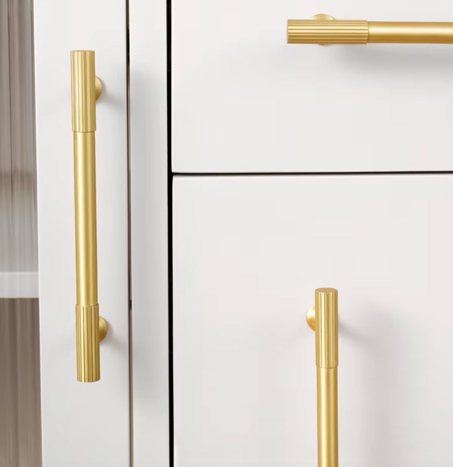 Gold-toned bar cabinet handles mounted on white drawers, shown in a close-up interior view.