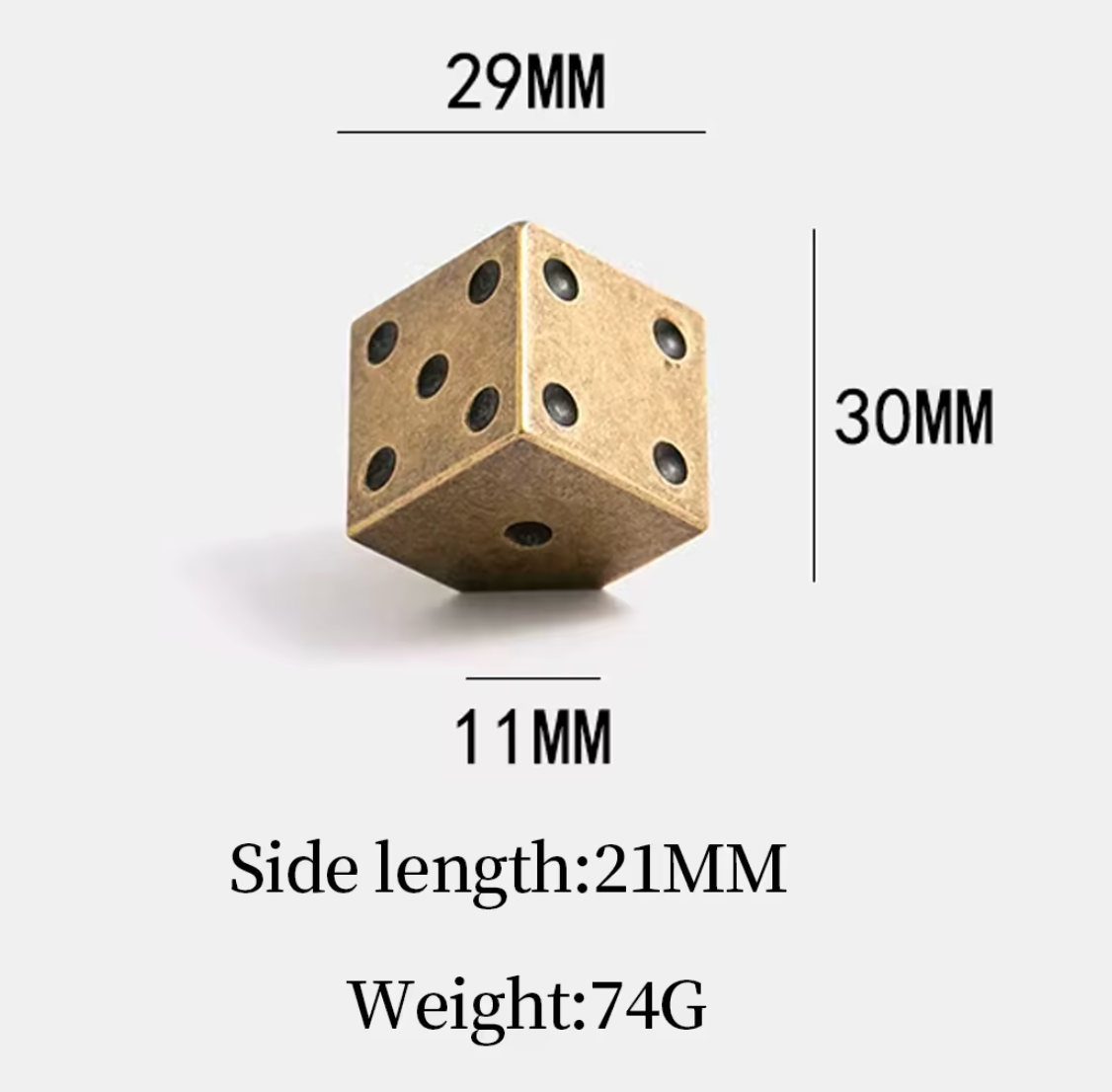 A brass-colored die with black printed dots, shown with dimension lines and text indicating side length 21mm, 29mm, 30mm, and weight 74g on a light gray background.