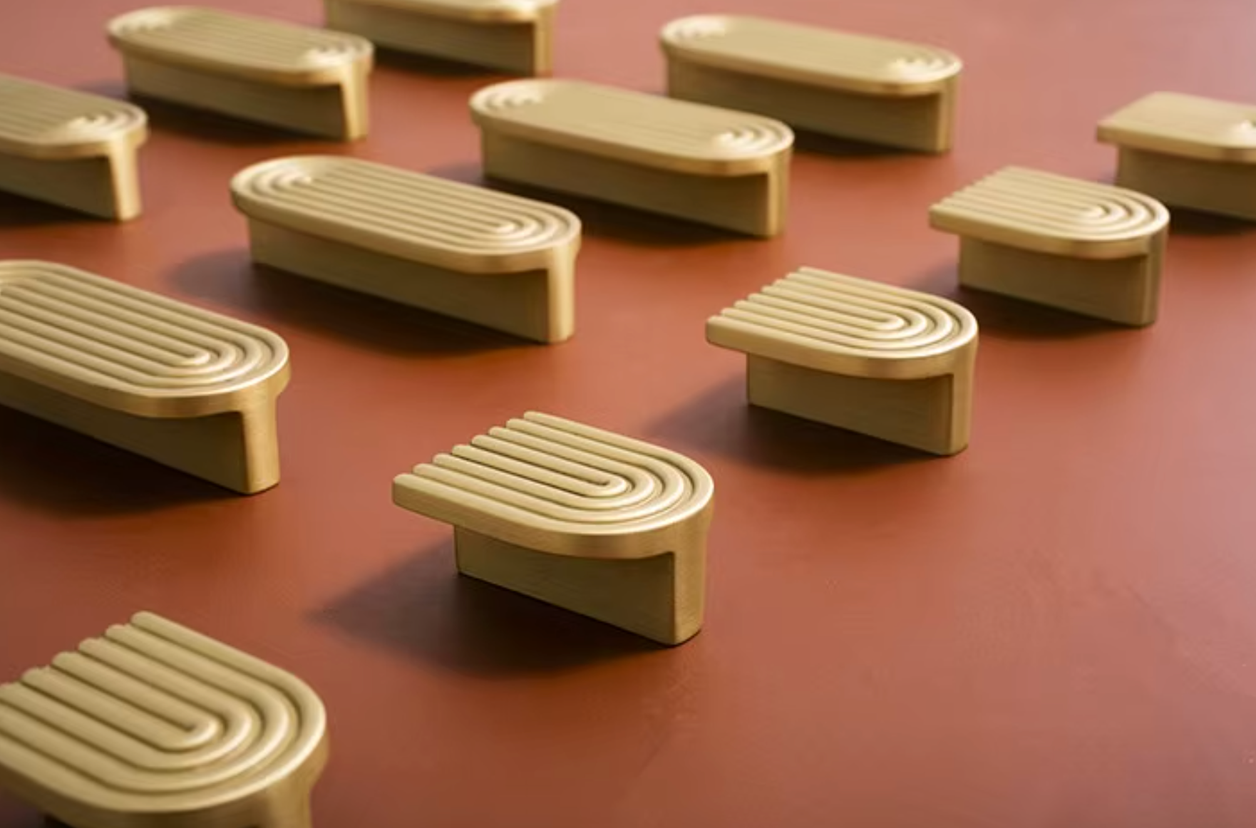 Multiple beige arched drawer pull knobs arranged on a warm reddish-brown surface.