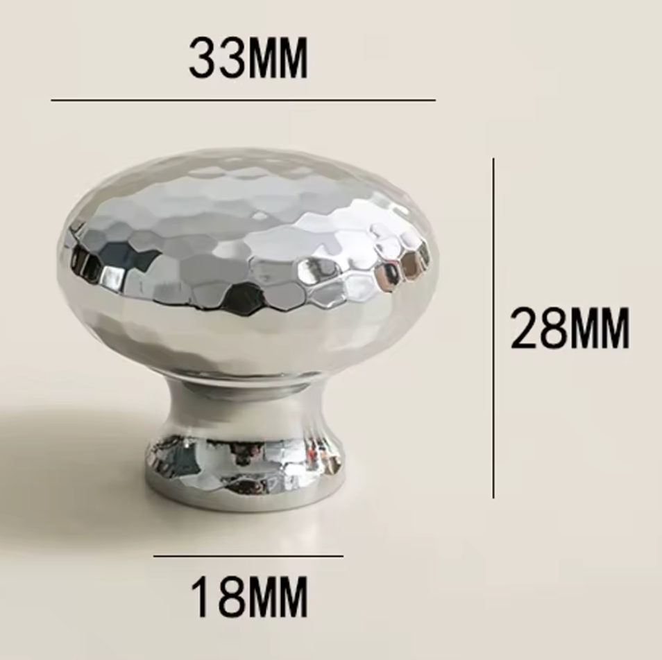 A shiny chrome cabinet knob with a hammered finish, shown with dimension lines and labels indicating a height of 28MM, width of 33MM, and base diameter of 18MM on a light beige background.