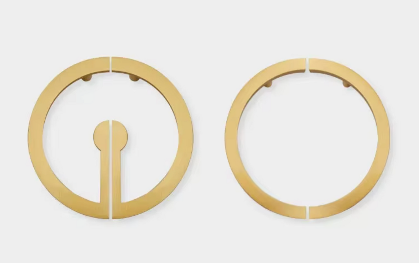Two gold-toned circular metal hardware pieces with split rings and small mounting holes, shown on a plain light gray background.