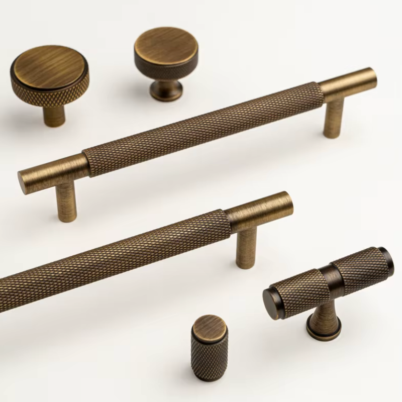 A set of antique bronze cabinet hardware, including two round knobs, two horizontal bar pulls with knurled grips, and two cylindrical pulls, displayed on a clean white background.