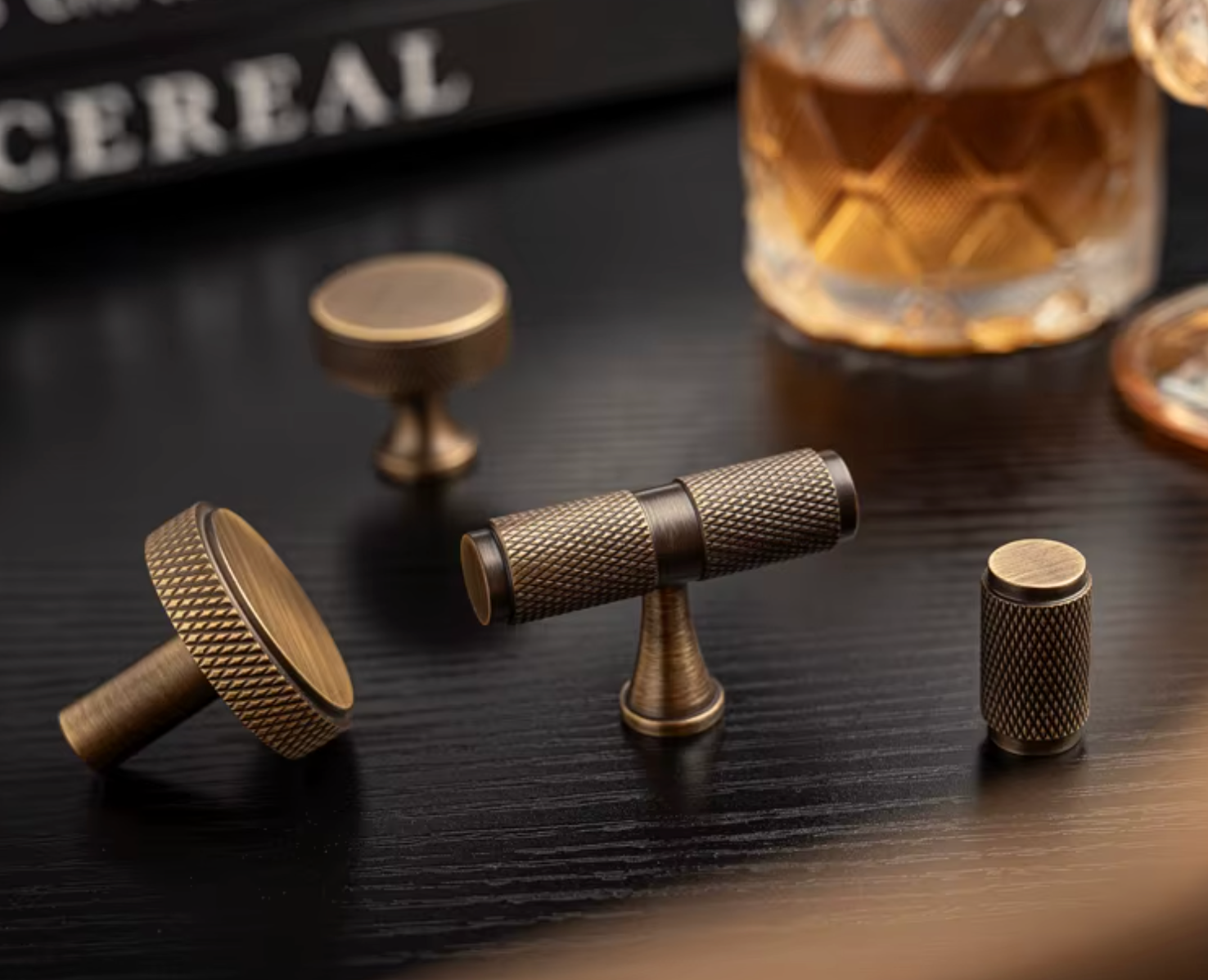 Three brass cabinet knobs with a textured, vintage finish displayed on a dark wooden tabletop .