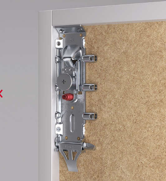 Close-up of a silver metal door lockset and latch mechanism mounted on a white door frame next to a textured beige wall.