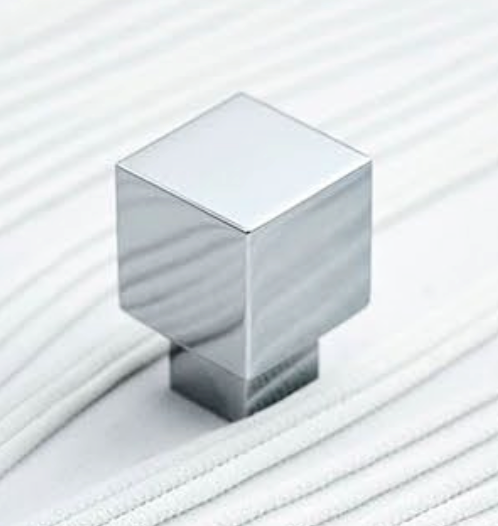 A polished chrome square cabinet knob with a stepped base, shown on a white ribbed fabric background.